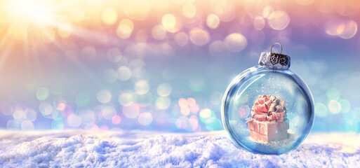 Red gift box in a snow ball on winter background