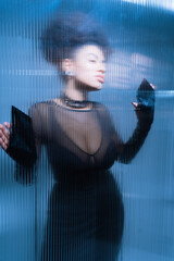 pretty african american model in black sexy outfit looking away while touching ruffled glass.