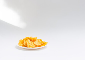 Corrugated potato chips on a white plate. White background. Isolate.