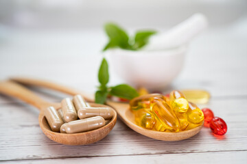 Vitamin C pills and vitamin E omega 3 fish oil on wooden spoon for good health.