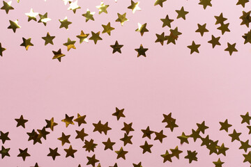 Golden confetti stars on color background, top view