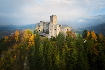 Fototapeta na wymiar Aerial view of Strecno Castle. Medieval castle standing on high calcite cliff above the river Vah. Dramatic view of castle in autumn mountain scape, lit by ray of sun. Monuments concept, Slovakia.