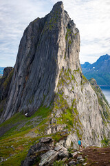 backpacker girl hiking on hesten overlooking Norway's famous segla mountain, senja island; hesten trail head, Norway's famous fjords with mighty mountains above the sea