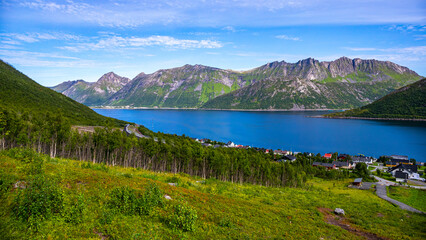 view from the hesten trailhead of the town of fjordegard and the mighty mountains in the norwegian fjord on the island of senja