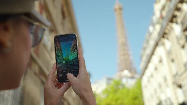 Attractive tourist taking photo of Eiffel Towers on mobile phone