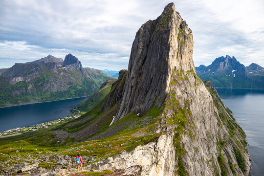 backpacker girl hiking on hesten overlooking Norway's famous segla mountain, senja island; hesten trail head, Norway's famous fjords with mighty mountains above the sea