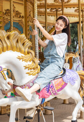 Fototapeta na wymiar Asian girl playing on the merry-go-round at an amusement park