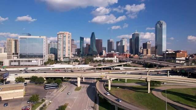 Fly toward famous Dallas Skyline with highway traffic under blue sky 
