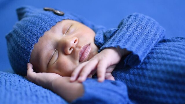 Beb&eacute; recien nacido dormido respirando placidamente vestido de azul 