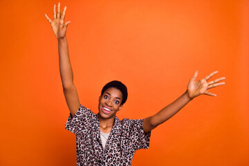 Photo of friendly cheerful person suddenly appears raise arms say hi isolated on orange color background