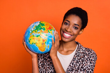 Photo of positive person hands hold globe toothy smile look camera isolated on orange color background