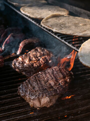 Juicy Ribeye steaks cooking on barbecue grill