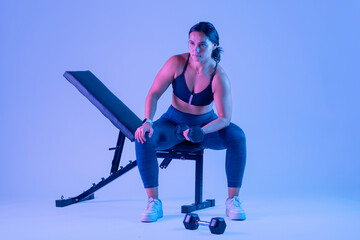 woman in sportswear doing biceps exercises, sitting on a bench