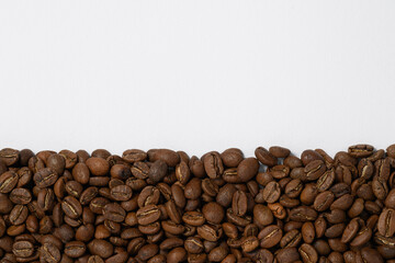 Coffee beans laid out in one wide row on a white background, place for inscription and advertising.