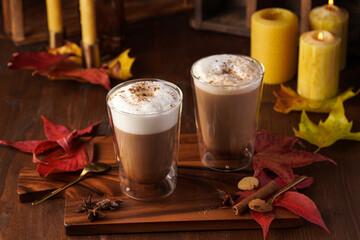 Two transparent glasses with cappuccino with black coffee, milk foam and cinnamon in autumn...