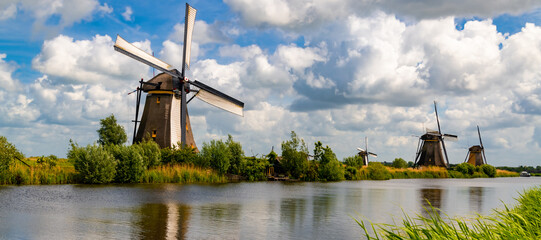 “Kinderdijk“ panorama with famous windmills is one of the best-known Dutch tourist sites and world heritage spot. Historic renovated wind water pumps in Netherlands on a sunny cloudy Spring day.
