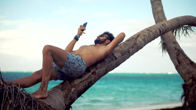 Tan Man Relaxing On Vacation Caribbean Tropical Beach. Tanned Man Lies On Palm Tree Vacation. Summer Sunbathing Resort Sea Or Ocean. Happy Traveler Resting Beach Hotel Luxury. Guy Lying On Ocean Vibes