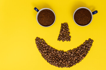 A smiling emoticon, lips made of coffee beans, and eyes made of coffee cups.