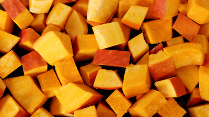 Chopped red kuri squash chunks background texture.