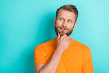 Photo of good mood thoughtful man blond hairstyle dressed orange t-shirt look empty space finger...
