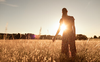 carefree woman walking in the field finding peace and solitude in nature. 