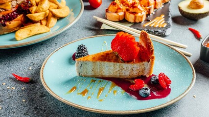 Close-up shot of a berry cheesecake on a blue plate on a table with various dishes and desserts