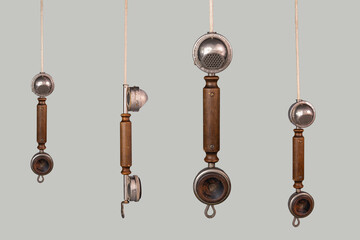 Set of antique wooden handsets with metal microphone and speaker. Aged telephone receivers hanging from cords on a gray background. Communication, telecommunication, conversation apparatus. - obrazy, fototapety, plakaty