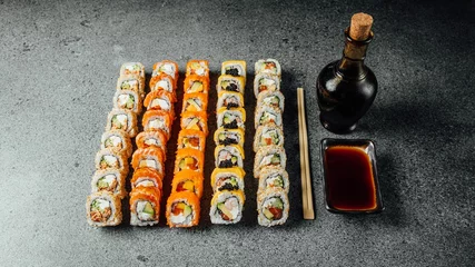 Fotobehang Set of delicious fresh sushi rolls, chopsticks, and soy sauce on a  gray surface © Aleksandrs Muiznieks/Wirestock Creators