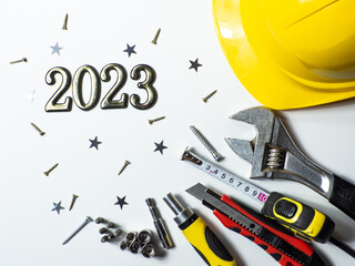 2023 with construction tools, hard hat on white background with small stars and copy space. New...