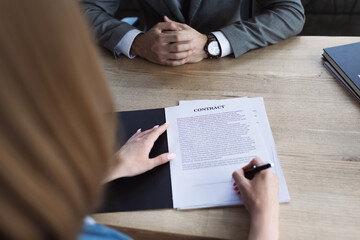 Cropped view of candidate signing contract near businessman during job interview.