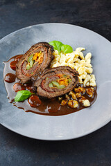 Traditionelle deutsche Wagyu Rinderrouladen mit Spätzle in würziger Bratensoße serviert als close-up auf einem Nordic Design Teller