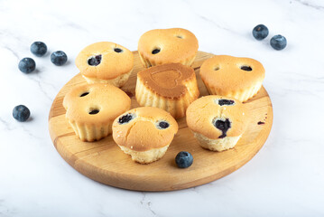 Homemade cupcakes with blueberries on a cutting board.