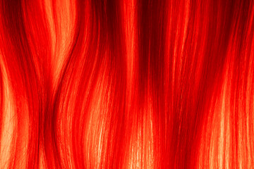 Texture of blonde combed hair illuminated by red light. Strands of light woman hair. Curl of healthy natural female hair. Synthetic wig. Macro shot of long straight locks of hair.