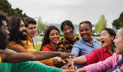 Happy young multiethnic people stacking hands in the city