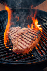 Barbecues dry aged Wagyu Porterhouse Steak vom Rind gegrillt als close-up auf einem Holzkohle Grill mit Feuer und Rauch
