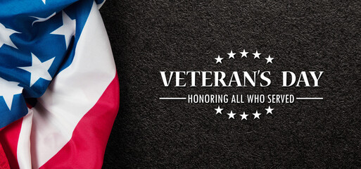 Fototapeta na wymiar Closeup of American flag with Text Veterans Day Honoring All Who Served on black textured background. American holiday banner.