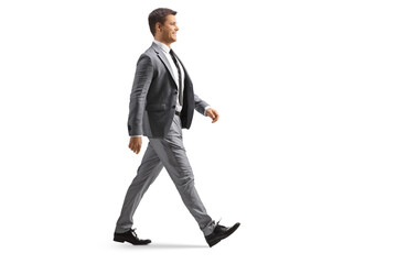 Full length profile shot of a young professional man in a gray suit walking