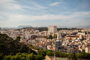 Fototapeta na wymiar Panorámica del paisaje de la ciudad de Alicante con sus edificios y su parque bajo un cielo azul con algunas nubes en el último viaje de trabajo. 