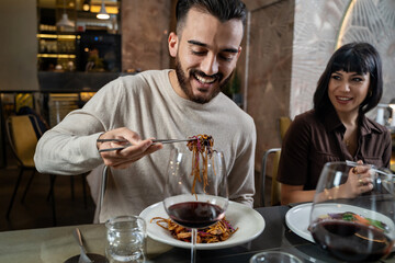 Happy couple at restaurant eating noodles at asian fusion food restaurant