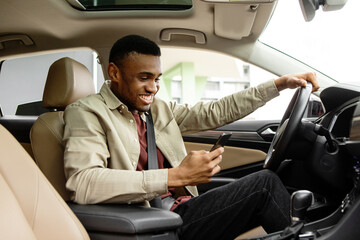 Smiling man or driver driving car and using smartphone.Transport, vehicle and technology concept 