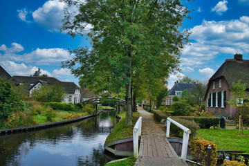 Fototapeta na wymiar The picturesque Dutch village of Giethoorn, with a canal, narrow wooden bridges, trees and thatched old farmhouses. 