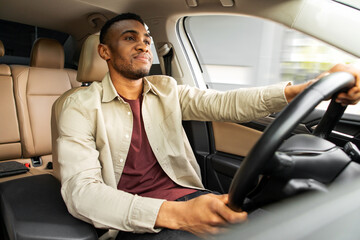  Portrait of a serious african american man driving a car with a beige interior