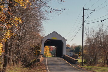 White Wooden Covered Bridge on Country Road in Autumn with Colored Leaves