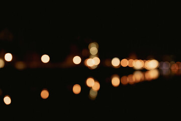 Defocused street lamps and reflection on a water, night city life. Gdansk, Poland, Europe