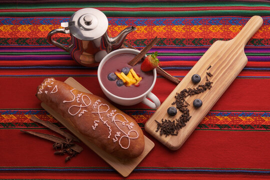 Colada morada y guagua de pan sobre mesa t&iacute;pica ecuatoriana