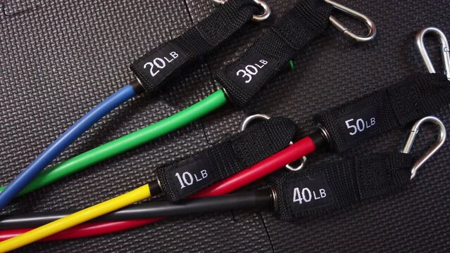 Close up of resistance exercise bands of various colors and weight, on top of a black gym mat