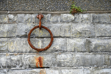 Old rusty metal mooring ring on an old wall. Metal rusty chain on stonewall.