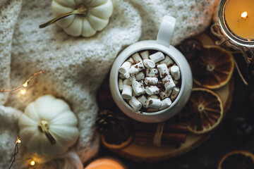 Autumn cozy home composition with hot chocolate with marshmallow and candles. Aromatherapy on a grey fall morning, atmosphere of cosiness and relax. Wooden background, window sill, close up.