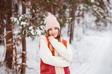 Portrait of beautiful romantic young woman in white sweater, light pink hat, woolen orange vest...