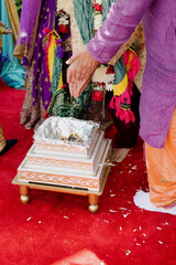 People having traditional Indian ritual, pouring rice inro box, celebrating wedding